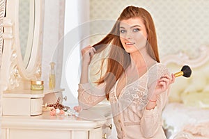 Beautiful young woman sitting near dressing table at home