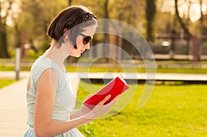 Beautiful young woman sitting in the park and reading