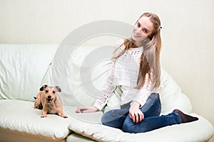 Beautiful young woman sitting on sofa with a dog