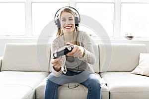 Beautiful young woman sitting on sofa with game controller