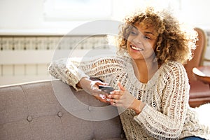 Beautiful young woman sitting on sofa with mobile phone