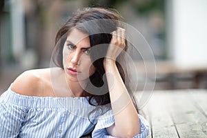 A beautiful young woman sitting at the table at a city park, looking into the distance