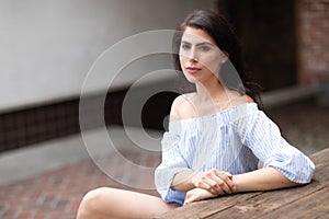A beautiful young woman sitting at the table at a city park, looking into the distance