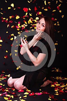 Beautiful young woman sitting under the falling petals