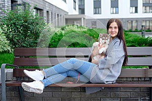 Beautiful young woman sitting on wooden bench and enjoy with her cute little dog husky