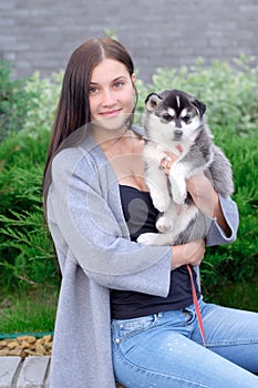 Beautiful young woman sitting on wooden bench and enjoy with her cute little dog husky