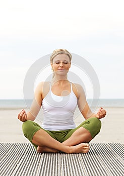 Beautiful young woman sitting in yoga pose outdoors