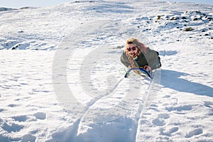 Beautiful young woman sledding happy in the snow