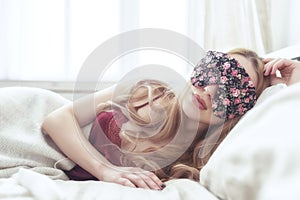 Beautiful young woman sleeping in her bed at home with blindfold eye mask.