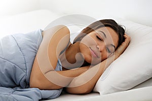 Beautiful young woman sleeping while lying in bed comfortably and blissfully.