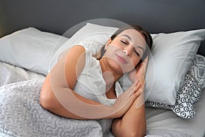 Beautiful young woman sleeping while lying in bed comfortably and blissfully