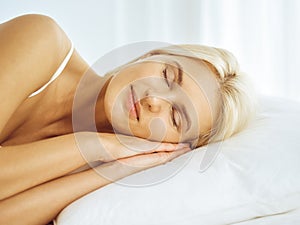 Beautiful young woman sleeping while lying in bed comfortably and blissfully. Good morning concept