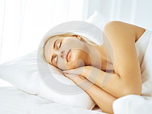 Beautiful young woman sleeping while lying in bed comfortably and blissfully. Good morning concept