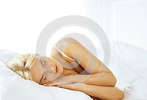 Beautiful young woman sleeping while lying in bed comfortably and blissfully. Good morning concept