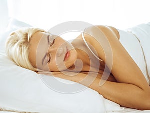 Beautiful young woman sleeping while lying in bed comfortably and blissfully. Good morning concept