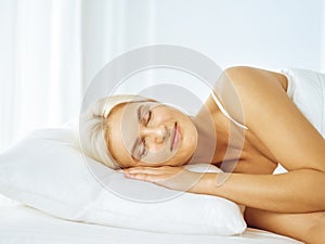 Beautiful young woman sleeping while lying in bed comfortably and blissfully. Good morning concept