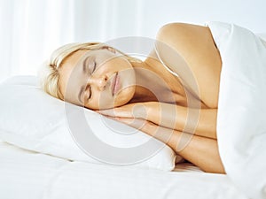 Beautiful young woman sleeping while lying in bed comfortably and blissfully. Good morning concept