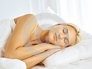 Beautiful young woman sleeping while lying in bed comfortably and blissfully. Good morning concept