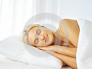 Beautiful young woman sleeping while lying in bed comfortably and blissfully. Good morning concept