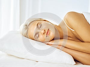 Beautiful young woman sleeping while lying in bed comfortably and blissfully. Good morning concept