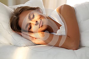 Beautiful young woman sleeping while lying in bed comfortably and blissfully. Sunbeam dawn on her face