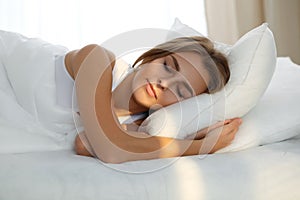 Beautiful young woman sleeping while lying in bed comfortably and blissfully Sunbeam dawn on her face