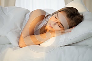 Beautiful young woman sleeping while lying in bed comfortably and blissfully Sunbeam dawn on her face