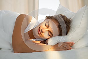 Beautiful young woman sleeping while lying in bed comfortably and blissfully Sunbeam dawn on her face