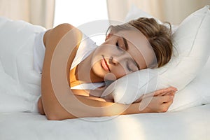 Beautiful young woman sleeping while lying in bed comfortably and blissfully Sunbeam dawn on her face