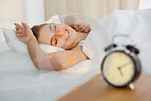 Beautiful young woman sleeping while lying in bed comfortably and blissfully Sunbeam dawn on her face