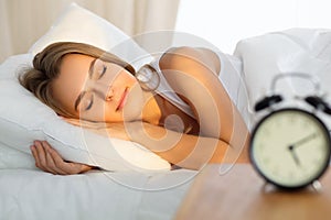 Beautiful young woman sleeping while lying in bed comfortably and blissfully Sunbeam dawn on her face