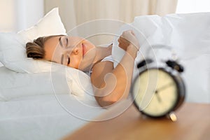 Beautiful young woman sleeping while lying in bed comfortably and blissfully Sunbeam dawn on her face