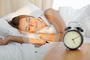 Beautiful young woman sleeping while lying in bed comfortably and blissfully Sunbeam dawn on her face