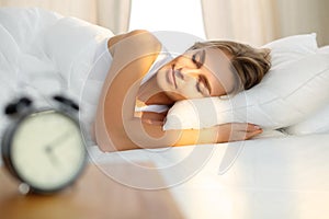 Bellissimo giovane donna dormire mentre sdraiarsi un letto comodamente un raggio di sole alba su di lei 