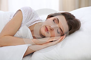 Beautiful young woman sleeping while lying in her bed and relaxing comfortably. It is easy to wake up for work or the