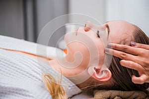 Beautiful young woman sleeping and relaxing with face massage and treatment in spa salon