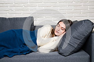 Beautiful young woman is sleeping and seeing sweet dreams on sofa at home