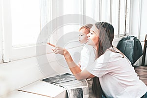 Beautiful young woman with small child sit near the window