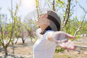 Beautiful young woman smiling cheerful with open arms and eyes closed relaxing and enjoying sunbathe in a sunny day of spring