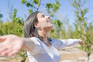 Beautiful young woman smiling cheerful with open arms and eyes closed relaxing and enjoying sunbathe in a sunny day of spring