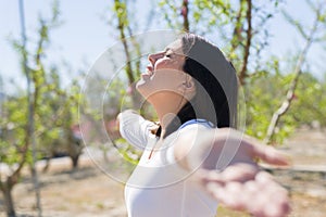 Beautiful young woman smiling cheerful with open arms and eyes closed relaxing and enjoying sunbathe in a sunny day of spring