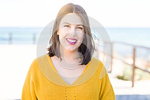 Beautiful young woman smiling cheerful walking by the sea on promenade, casual pretty girl close to the sea on sunny day