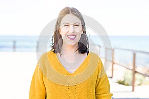 Beautiful young woman smiling cheerful walking by the sea on promenade, casual pretty girl close to the sea on sunny day