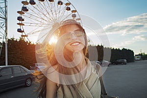 A beautiful young woman smiling cheerfully in front of a ferris wheel