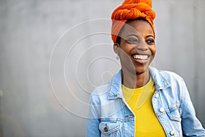 Beautiful young woman smiling in front of gray wall