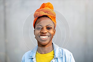 Beautiful young woman smiling in front of gray wall