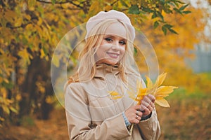 Beautiful young woman smiling holding autumn yellow leaves outdoors