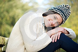 Beautiful young woman smiling outdoors with sweater and hat