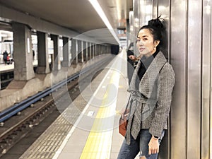 Beautiful young woman with smiling waiting a train at subway station