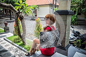 Beautiful young woman with snakeskin python leather handbag posing in sunglasses. Tropical Bali island, Indonesia.